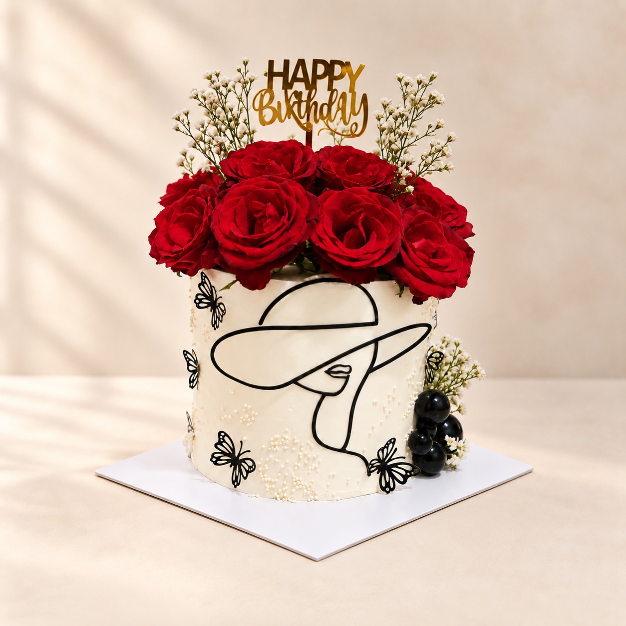 Janet’s white celebration cake with red roses, butterflies, and a gold birthday topper